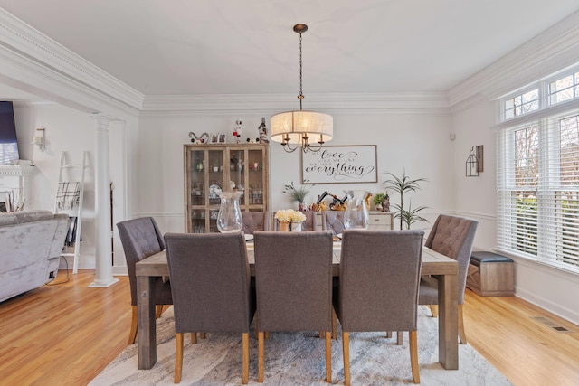 dining room featuring hardwood / wood-style floors, crown molding, and ornate columns