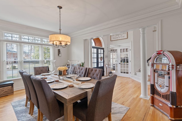 dining area with crown molding, light hardwood / wood-style floors, french doors, and ornate columns