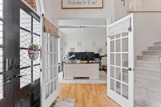 interior space with crown molding, light hardwood / wood-style flooring, and french doors