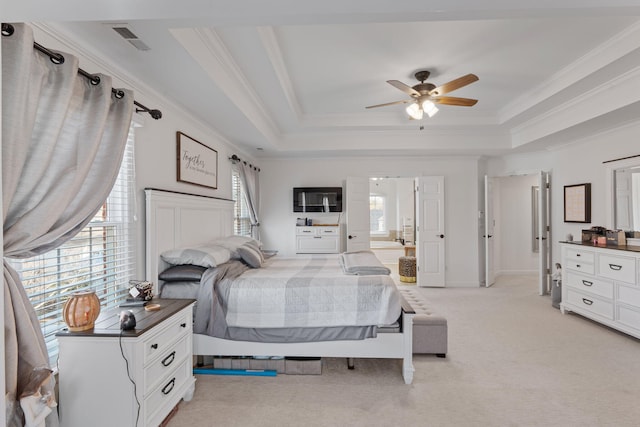 bedroom with ensuite bath, light carpet, a tray ceiling, ceiling fan, and multiple windows