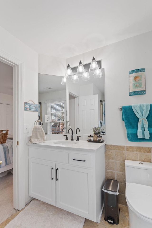 bathroom featuring vanity, tile walls, and toilet