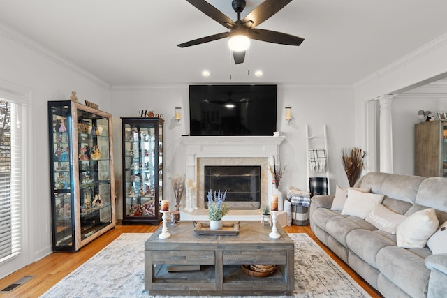 living room featuring ceiling fan, ornamental molding, decorative columns, and light hardwood / wood-style flooring