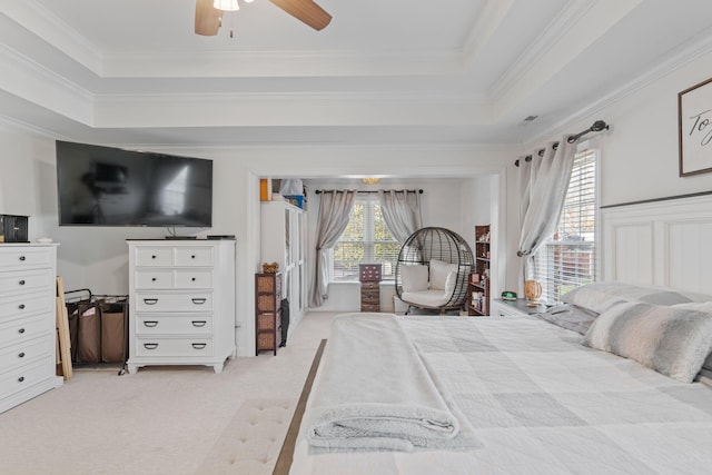 bedroom featuring light carpet, a tray ceiling, crown molding, and ceiling fan