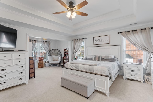 bedroom featuring multiple windows, light colored carpet, a raised ceiling, and ceiling fan