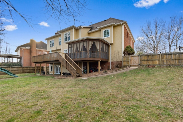 rear view of house featuring a wooden deck, a yard, a playground, and a sunroom