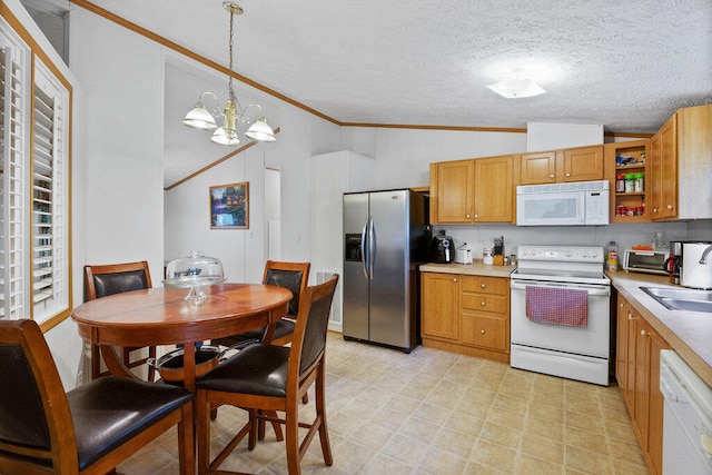 kitchen with a chandelier, a textured ceiling, vaulted ceiling, pendant lighting, and white appliances