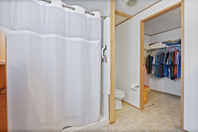 bathroom with toilet, a textured ceiling, and walk in shower