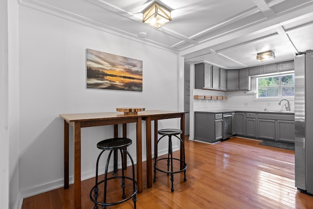 kitchen with gray cabinets, sink, light hardwood / wood-style floors, and stainless steel fridge