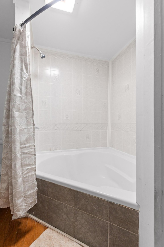 bathroom with shower / bath combo with shower curtain, a skylight, and hardwood / wood-style floors