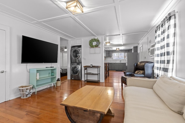 living room featuring coffered ceiling, sink, ceiling fan, hardwood / wood-style flooring, and stacked washer and dryer