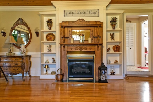 sitting room featuring wood-type flooring, ornamental molding, and built in shelves