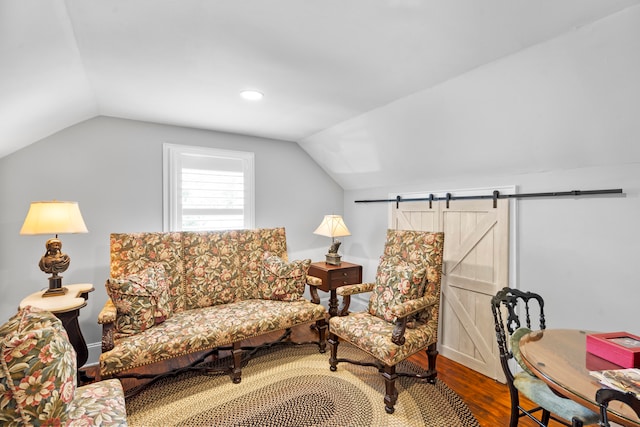 living room with a barn door, hardwood / wood-style floors, and vaulted ceiling