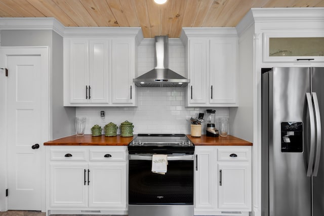 kitchen featuring decorative backsplash, appliances with stainless steel finishes, wall chimney exhaust hood, white cabinets, and butcher block countertops