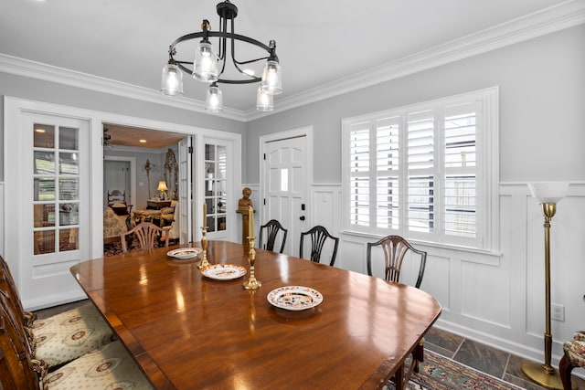 dining space featuring french doors, a wealth of natural light, crown molding, and a notable chandelier