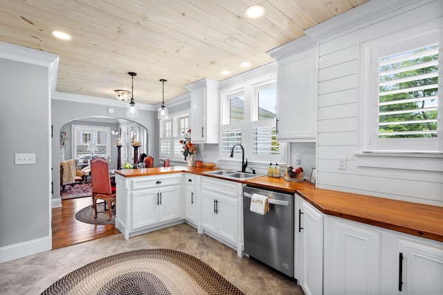 kitchen featuring sink, stainless steel dishwasher, butcher block countertops, decorative light fixtures, and kitchen peninsula