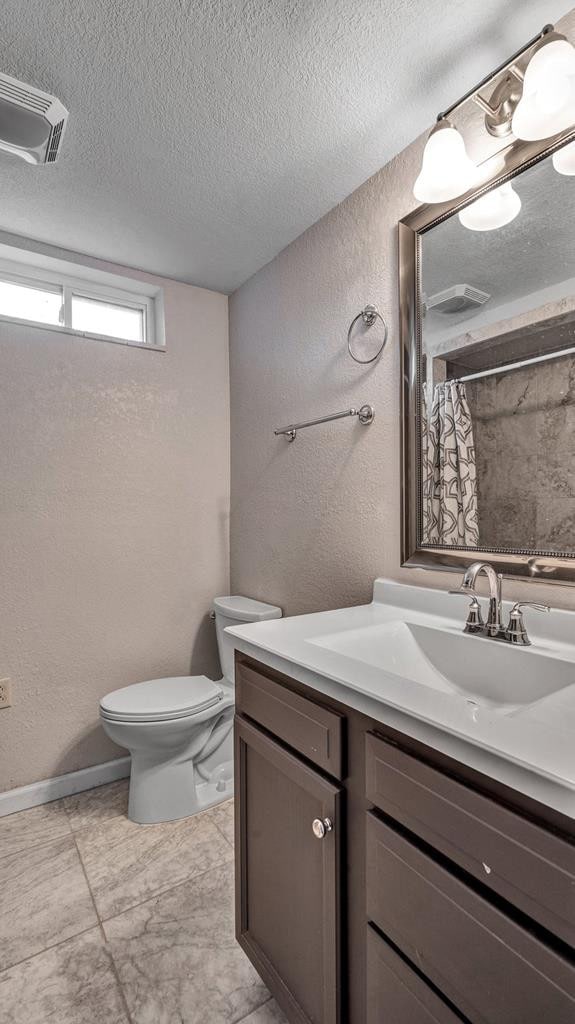 bathroom with a shower with shower curtain, tile patterned floors, vanity, a textured ceiling, and toilet