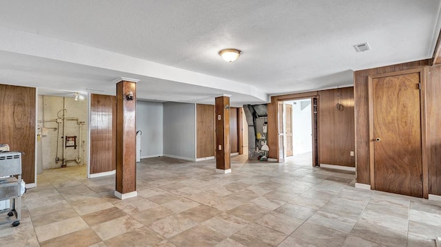 basement featuring wood walls and a textured ceiling