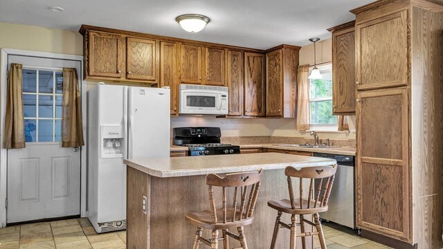 kitchen with a center island, sink, a kitchen breakfast bar, decorative light fixtures, and white appliances