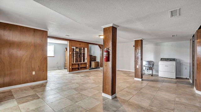 basement featuring washer / clothes dryer, wood walls, and a textured ceiling