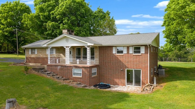 rear view of house featuring covered porch, central AC unit, and a lawn