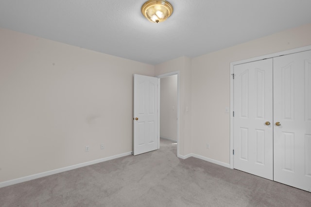 unfurnished bedroom featuring light colored carpet and a closet