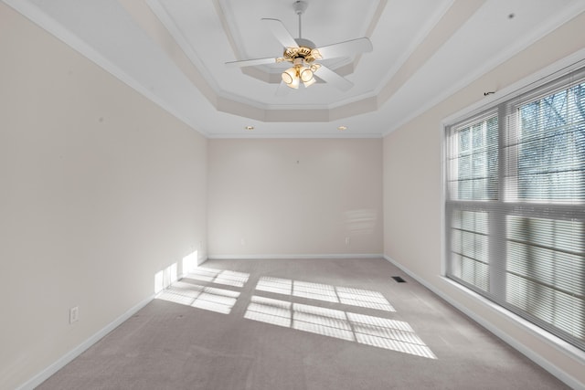 empty room with ceiling fan, crown molding, light carpet, and a raised ceiling