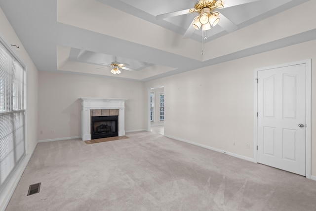 unfurnished living room featuring ceiling fan, a raised ceiling, a fireplace, and light carpet