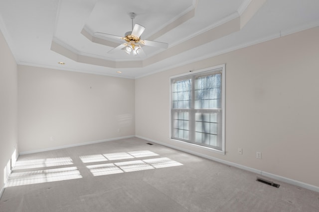 spare room with ceiling fan, a raised ceiling, crown molding, and light carpet