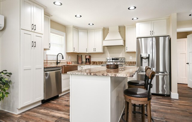 kitchen featuring appliances with stainless steel finishes, premium range hood, sink, a center island, and dark hardwood / wood-style floors