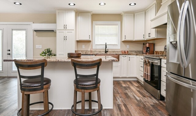 kitchen with a kitchen breakfast bar, a wealth of natural light, and appliances with stainless steel finishes