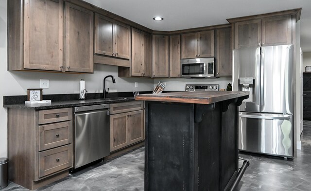 kitchen with dark brown cabinetry, sink, a kitchen island, and stainless steel appliances