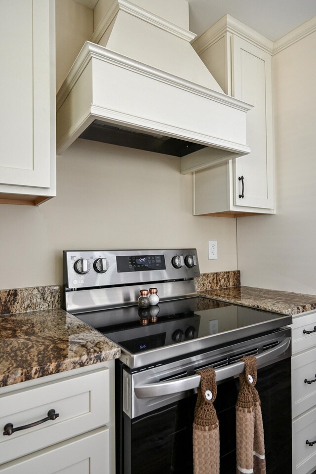 kitchen featuring custom exhaust hood, white cabinetry, dark stone countertops, and electric stove