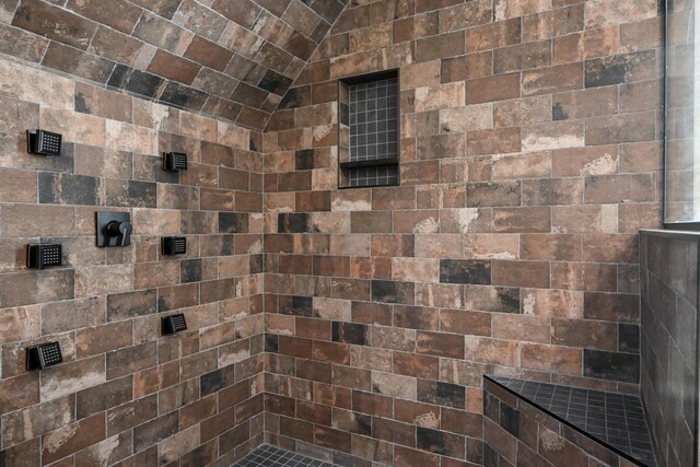 bathroom with a tile shower and lofted ceiling