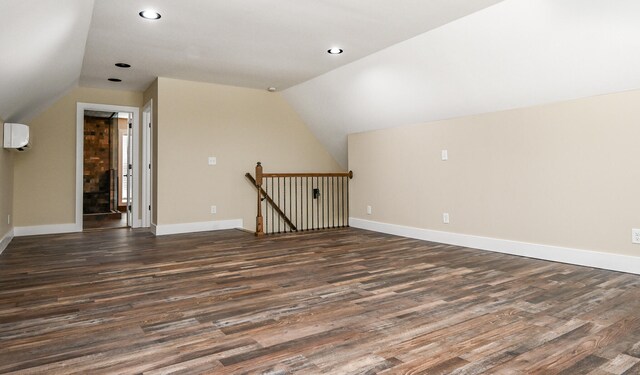 bonus room with dark hardwood / wood-style floors, lofted ceiling, and a wall unit AC