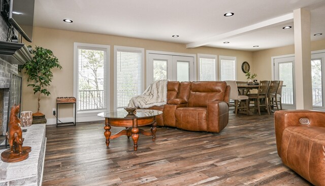 living room with dark hardwood / wood-style floors, beam ceiling, and a brick fireplace