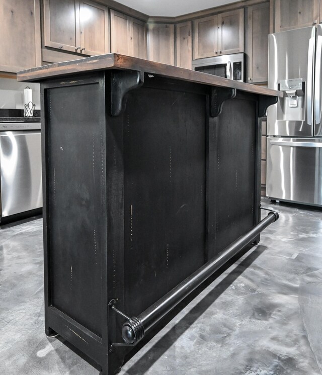 kitchen with a kitchen bar, dark brown cabinetry, and appliances with stainless steel finishes