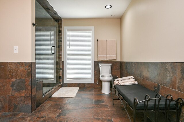 bathroom featuring an enclosed shower, toilet, and tile walls