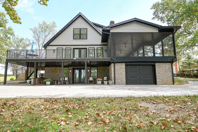 back of house with a sunroom, a garage, and a wooden deck