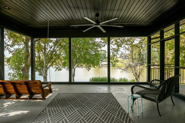 unfurnished sunroom with ceiling fan, a healthy amount of sunlight, and a water view