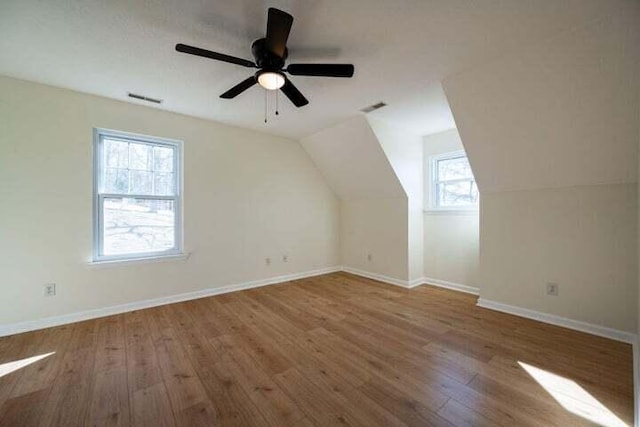 additional living space featuring baseboards, visible vents, vaulted ceiling, and wood finished floors
