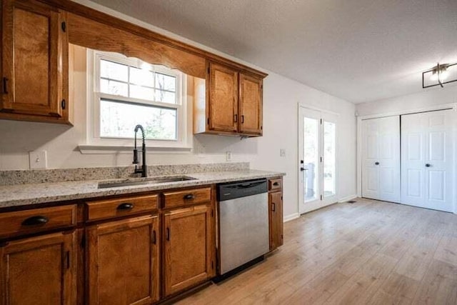 kitchen featuring light stone counters, brown cabinets, light wood-style flooring, a sink, and dishwasher