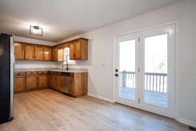 kitchen featuring light wood-style flooring, stainless steel appliances, a healthy amount of sunlight, light countertops, and brown cabinets