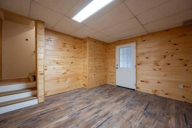 spare room featuring wood walls, a drop ceiling, and wood finished floors