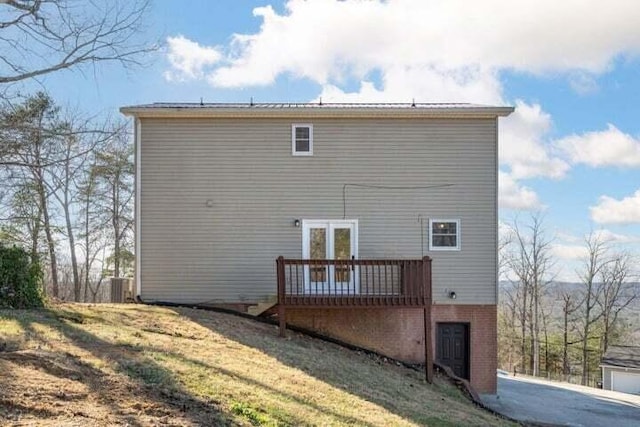 rear view of property featuring a yard, a deck, and brick siding