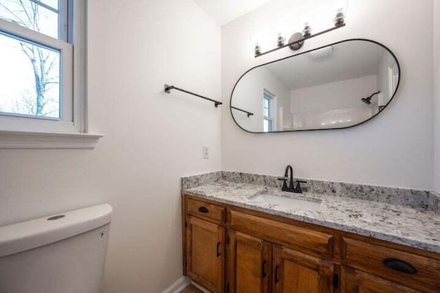 bathroom featuring a healthy amount of sunlight, vanity, and toilet