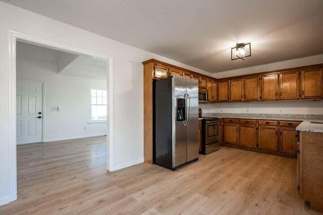 kitchen with baseboards, light wood-style flooring, brown cabinets, stainless steel appliances, and light countertops
