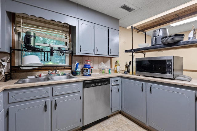 kitchen with tasteful backsplash, gray cabinetry, sink, and stainless steel appliances