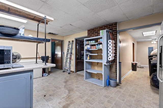 basement with a paneled ceiling and brick wall