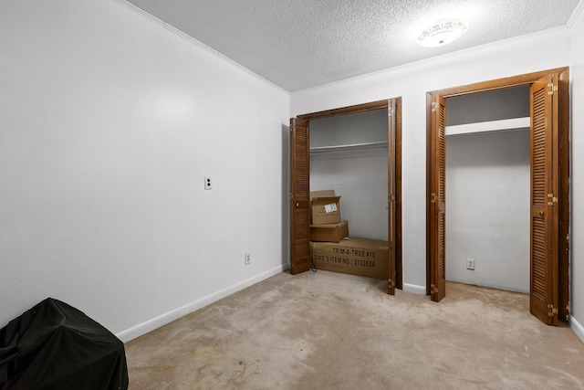 unfurnished bedroom featuring multiple closets, light colored carpet, and a textured ceiling