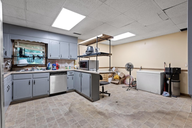 kitchen with kitchen peninsula, appliances with stainless steel finishes, backsplash, and a drop ceiling